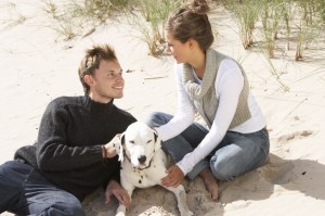A couple site together on the beach with a dog
